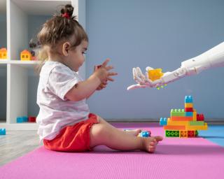 Little girl in child care plays with a robot. 