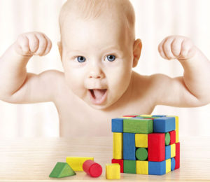 Infant raises fists while playing with blocks
