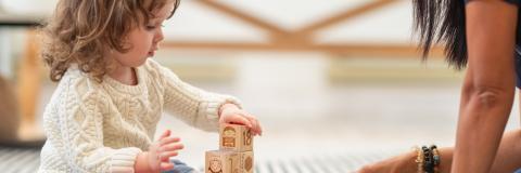 Little girl and child care provider playing with blocks. 