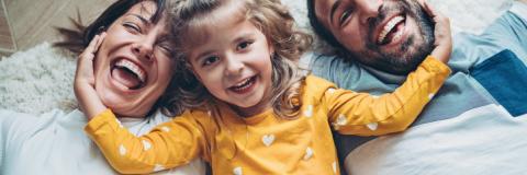April is National Child Abuse Prevention Month Happy parents and toddler laying on floor.