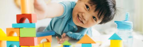 Laura's Blog GOFCC Happy little boy building with blocks.