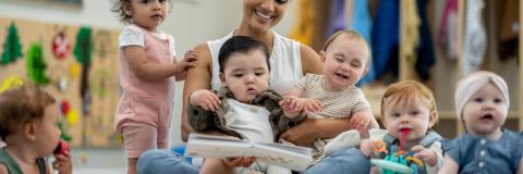 Child care unites us. Child care provider reading to four toddlers.