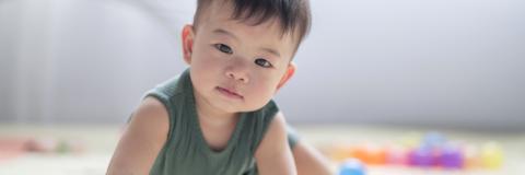 Accomplishments 25 Small Asian American child looking into camera in a green tanktop.