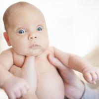 Baby staring intensely while being held by his parent. 