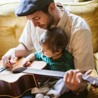 Dad and child practice guitar