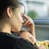 Stressed mother with sleeping baby. 