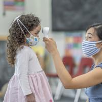 Child care provider taking a child's temperature.