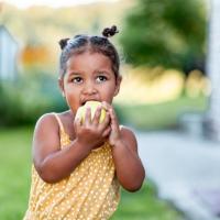 Little girl eating an apple.