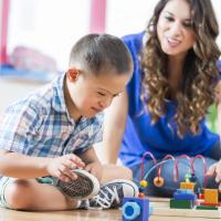 Little boy with Downs Syndrome and child care provider playing together. 