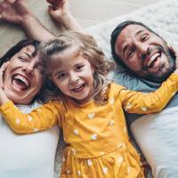 Happy parents and toddler laying on floor.