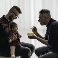 Two dads feeding their babies.