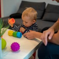 Baby looking at plastic blocks on a table.