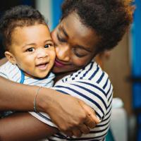 Adult hugging a happy toddler. 