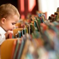 Little girl in a library looking at books. 