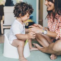 Mom helping her toddler son to learn how to use the potty. 