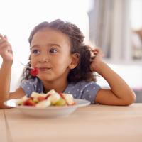 Little girl eating a fresh fruit salad. 