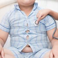 Little hand doctor checks heart of obese toddler boy with stethoscope, healthcare concept 