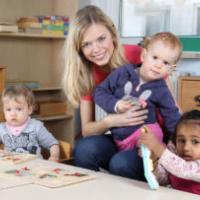 Childcare provider and three young children at the drawing table 