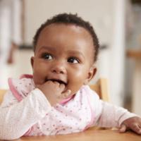 Cute Baby Girl Wearing Bib Sitting In High Chair 