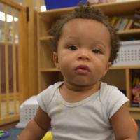 Toddler boy in onesie looks straight at camera 