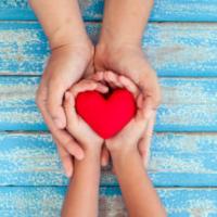 Red heart in child kid and mother hands on old blue wooden table in vintage retro style 