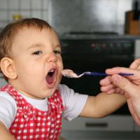 mother feeding baby girl, baby opens mouth wide 