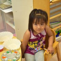 Young girl in classroom sits at table with empty objects 