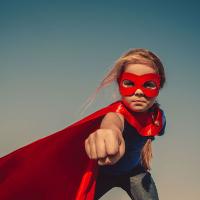 Funny little power super hero child (girl) in a red raincoat. Superhero concept.  