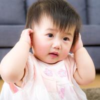 Disappointed little girl covering her ears isolated 