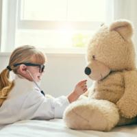 Shot of an adorable little girl dressed up as a doctor and examining a teddy bear with a stethoscope 