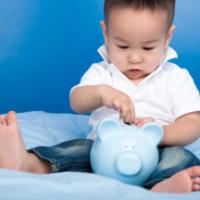 Boy putting money in blue piggy bank 