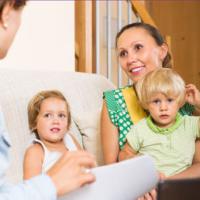 Home visitor interacting with happy mother with two children 