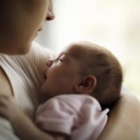 Mother holding her baby girl at home 