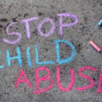 Colorful chalk drawing on asphalt: words STOP CHILD ABUSE 