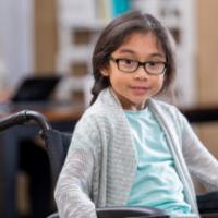 Pretty elementary age girl in wheelchair waits in doctor's office waiting room. 