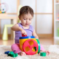 Toddler sitting on floor playing with a sorter toy 