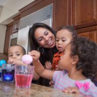 young family coloring easter eggs in kitchen 