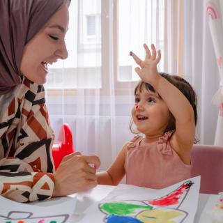 Little girl and child care provider coloring together