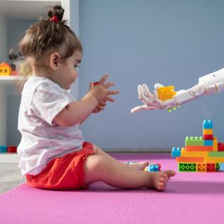 Little girl in child care plays with a robot. 