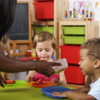 A portrait of a biracial toddler showing excitement at the prosprct of receiving more food at nursery. 