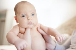 Baby staring intensely while being held by his parent. 