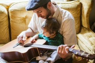 Dad and child practice guitar