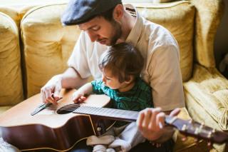 Music Soothes the Toddler Soul Dad and child practice guitar
