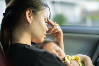 Stressed mother with sleeping baby. 