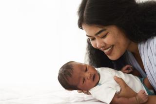 Mixed race African American and Asian mother holding her newborn baby with happy face.