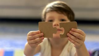 Young child with jigsaw puzzle pieces. 