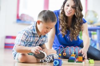 ACES and Children with Disabilities Little boy with Downs Syndrome and child care provider playing together.