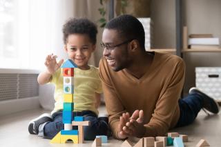 Male child care provider and little boy buillding together. 