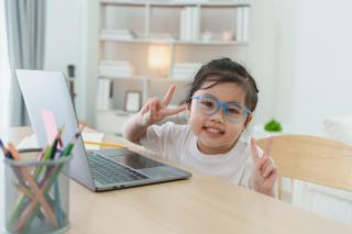 RFP Strategic Planning Initiative Toddler girl working at a laptop and flashing peace signs.