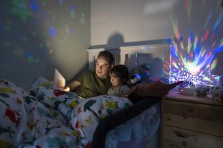 A Little Anxious When It'd Dark Dad reading a bedtime story to his son.